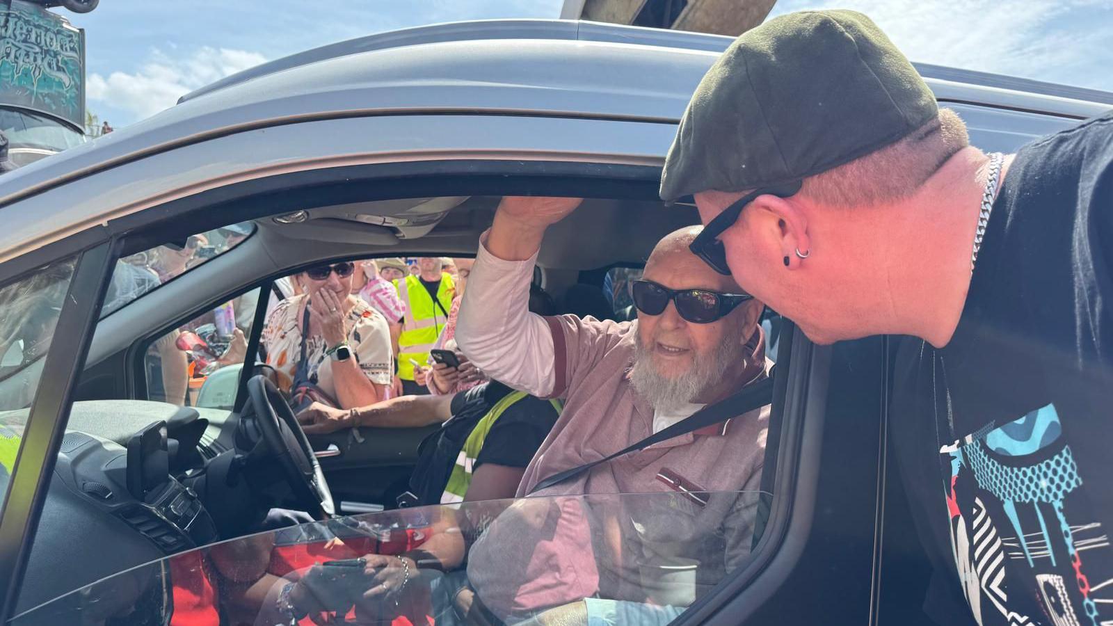 Michael Eavis sat in a car talking to artist Tommy the Vandalist.