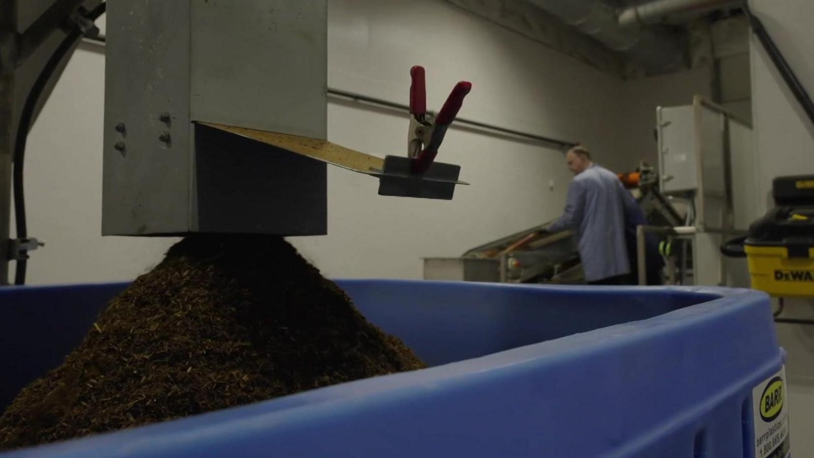 Compost yn dod allan o beiriant