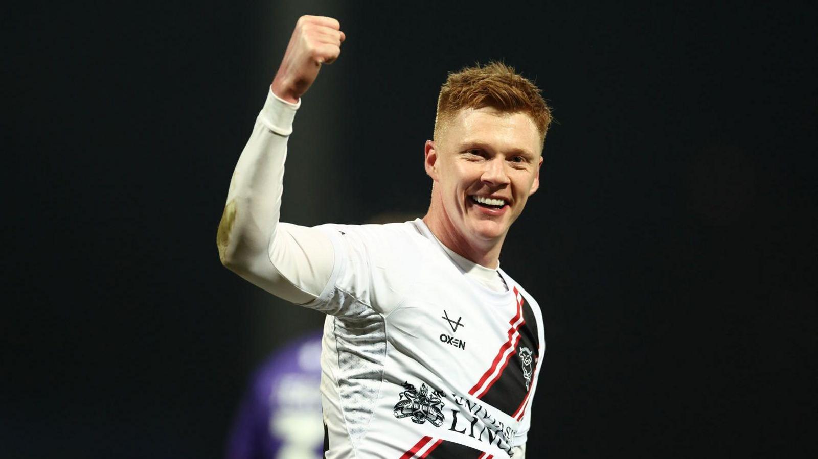 Sam Clucas holds up his right arm and makes a fist in celebration at scoring for Lincoln City