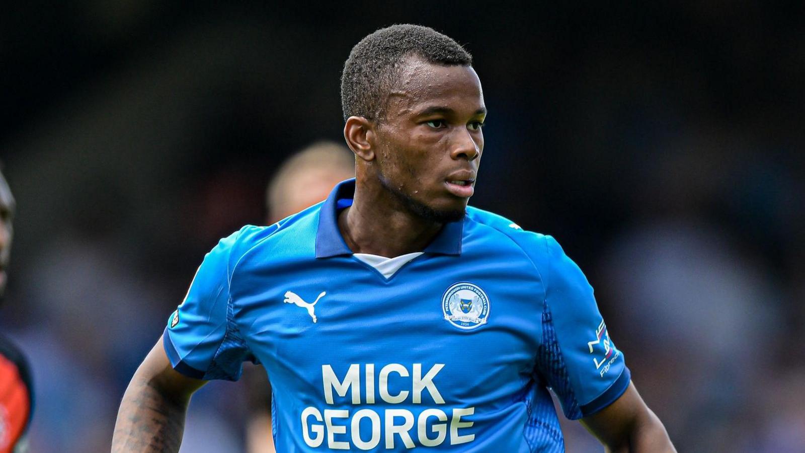 A close up of Bradley Ihionvien playing in his Peterborough blue home kit during a match against Luton Town in August