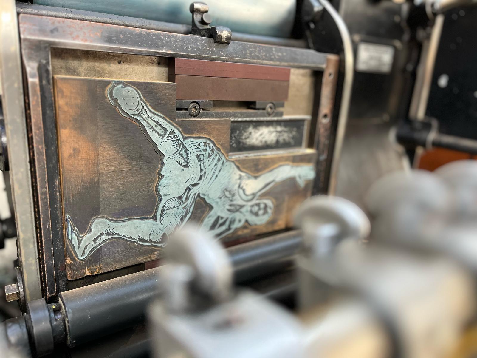 A section of a machine shows a metal plate with a photo of a sportsman etched into it, ready to print the image onto paper