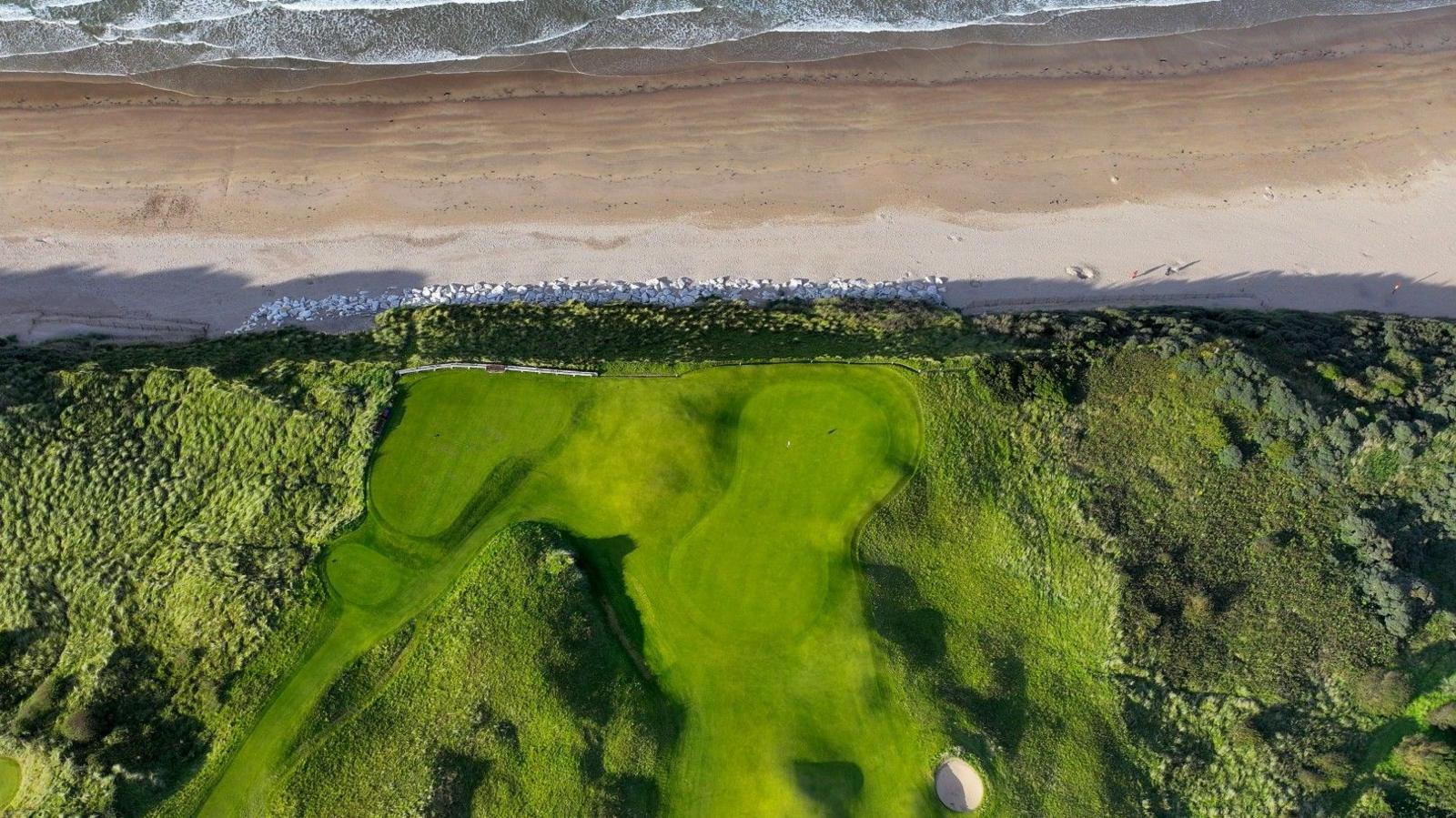 An overhead shot of the fifth green on the Dunluce course at Royal Portrush, with the beach and see just yards off the back of the green
