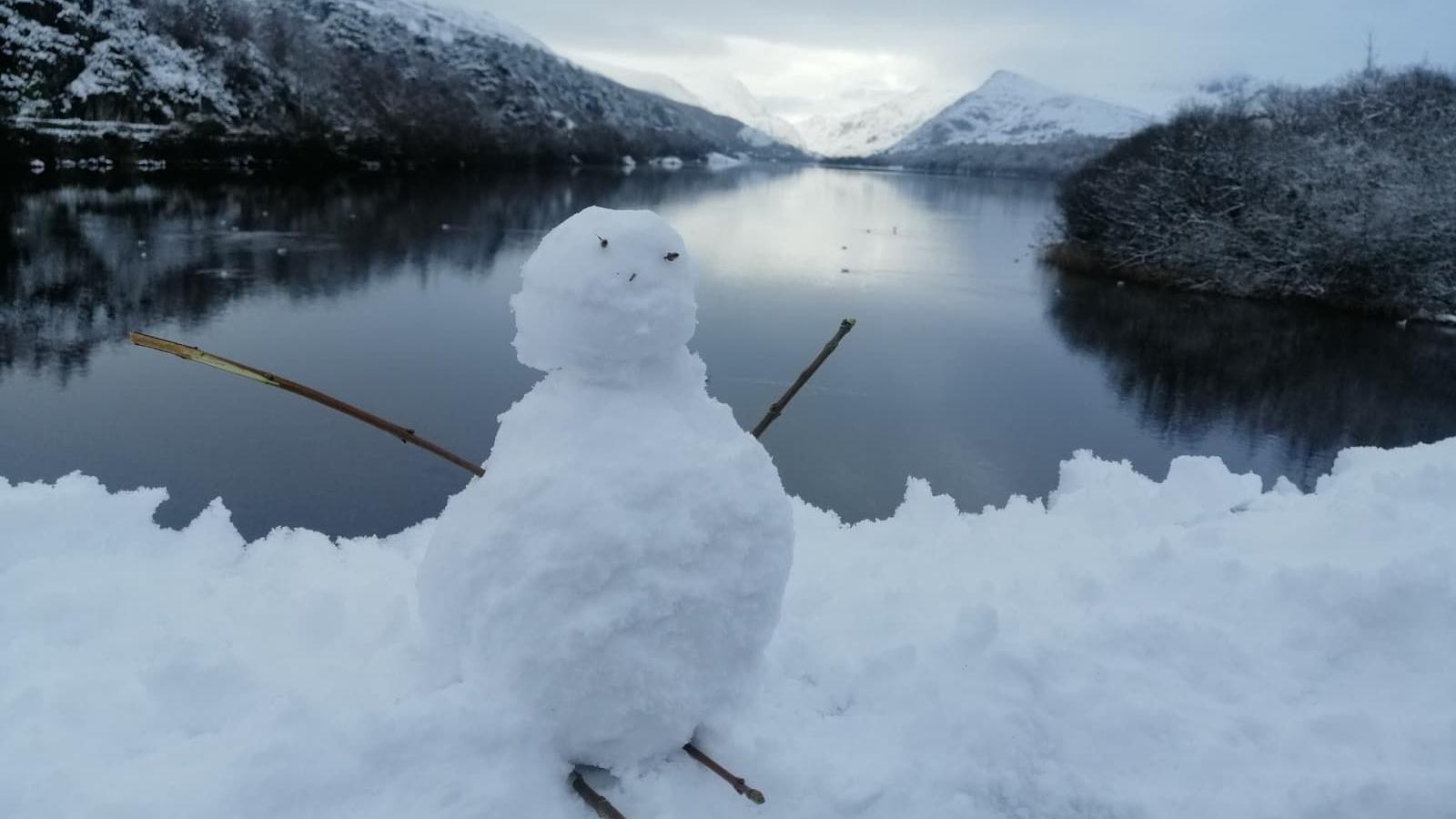 Dyn eira ar lan Llyn Padarn