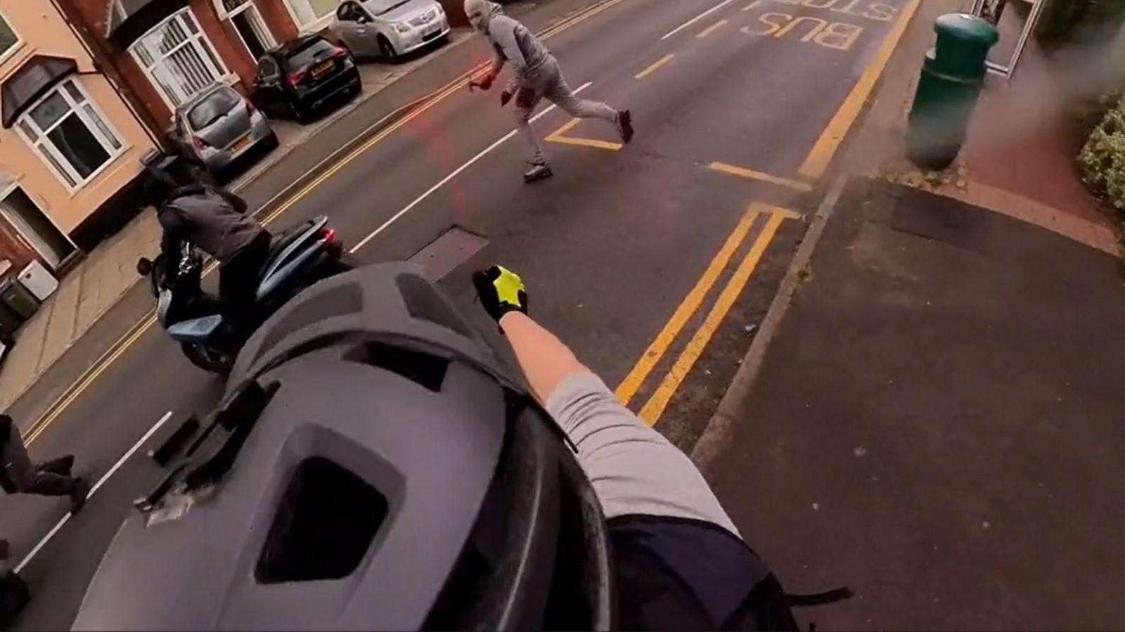 A cyclist is pictured by his helmet camera which shows him spraying a group of men with a red criminal identifier gel