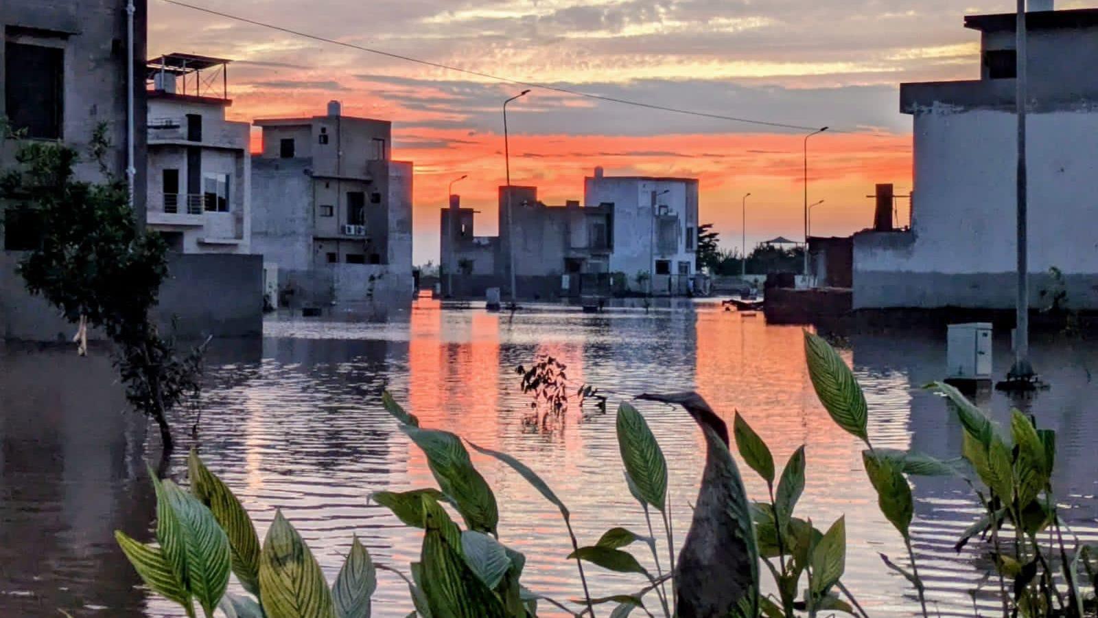 A wide shot of Shakil Salam's street, flooded. The sunset has painted a