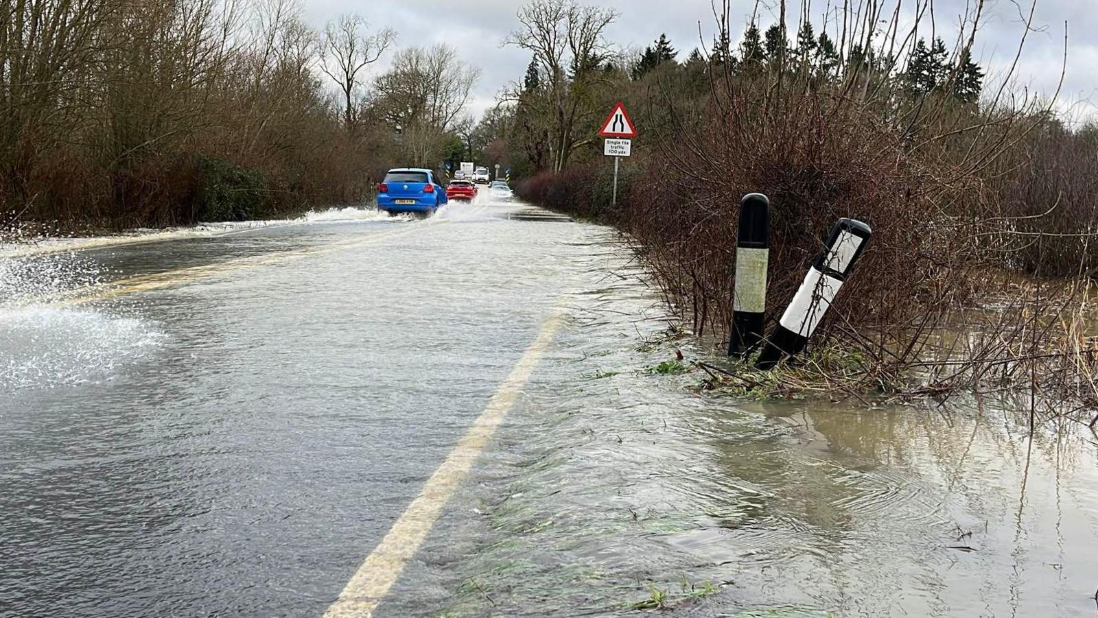 Flooding on the A272 road which runs west of Billinghurst in West Sussex. Cars can be seen attempting to travel through heavy rainwater in both directions. 