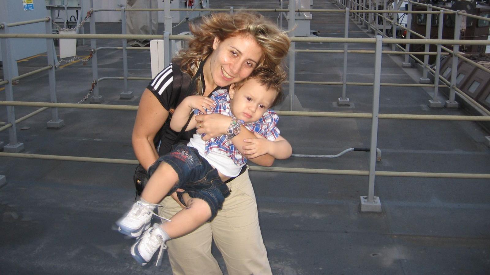 Nadia Ayoub McCullough outdoors with her son Thomas, pictured as a toddler. She is standing and holding him in front of her.