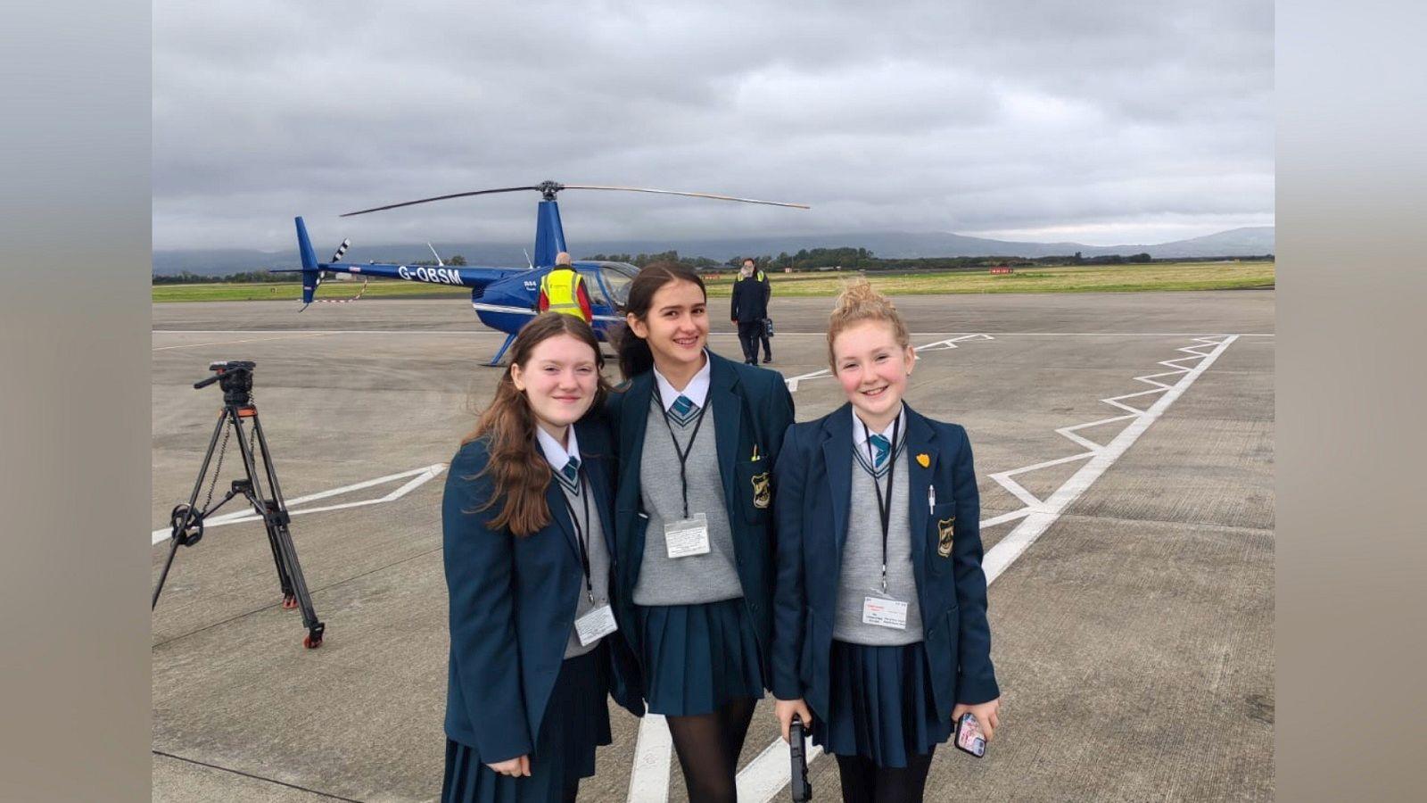 Three of the girls stand in front of the plane