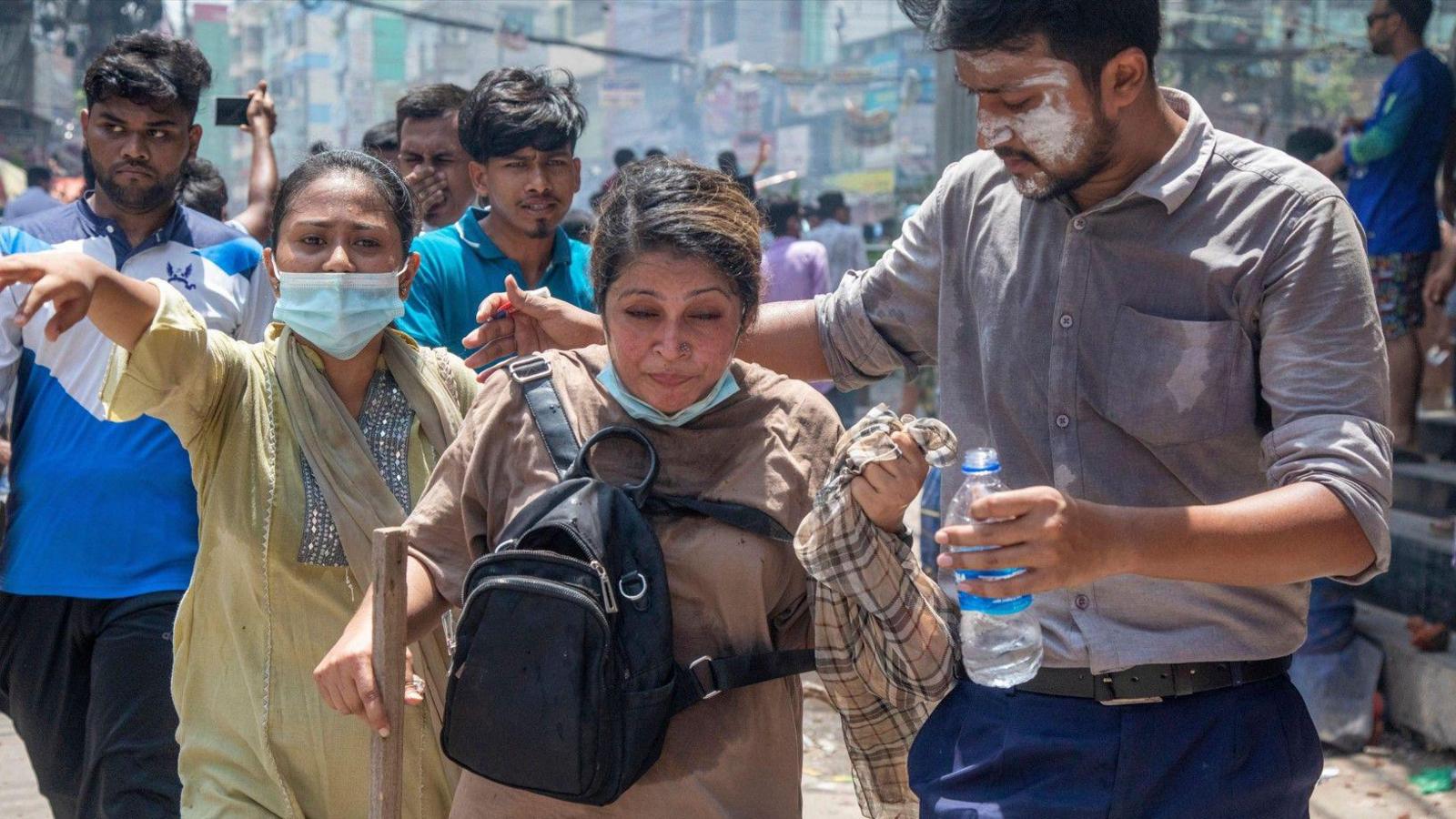 An injured person is assisted as demonstrators clash with police, Bangladesh Chhatra League (BCL) and Jubo League members, during ongoing quota students protests