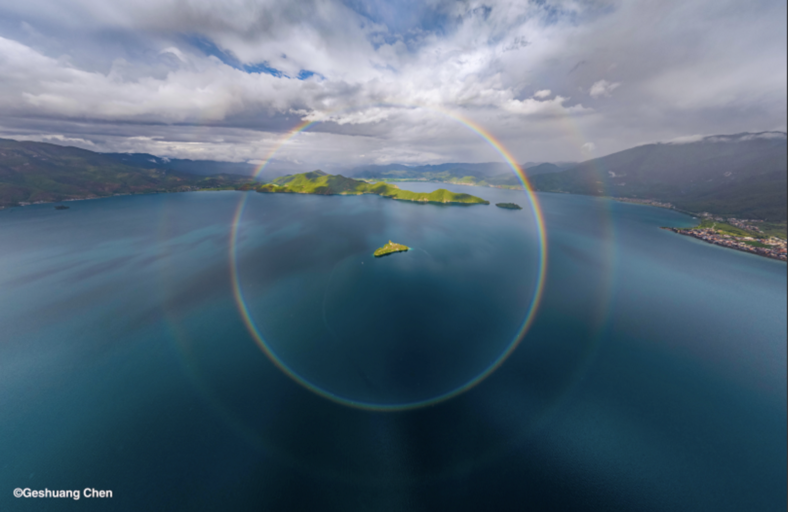 At Lugu Lake in China an image of a full circle rainbow frames an island in the centre of the lake. 
