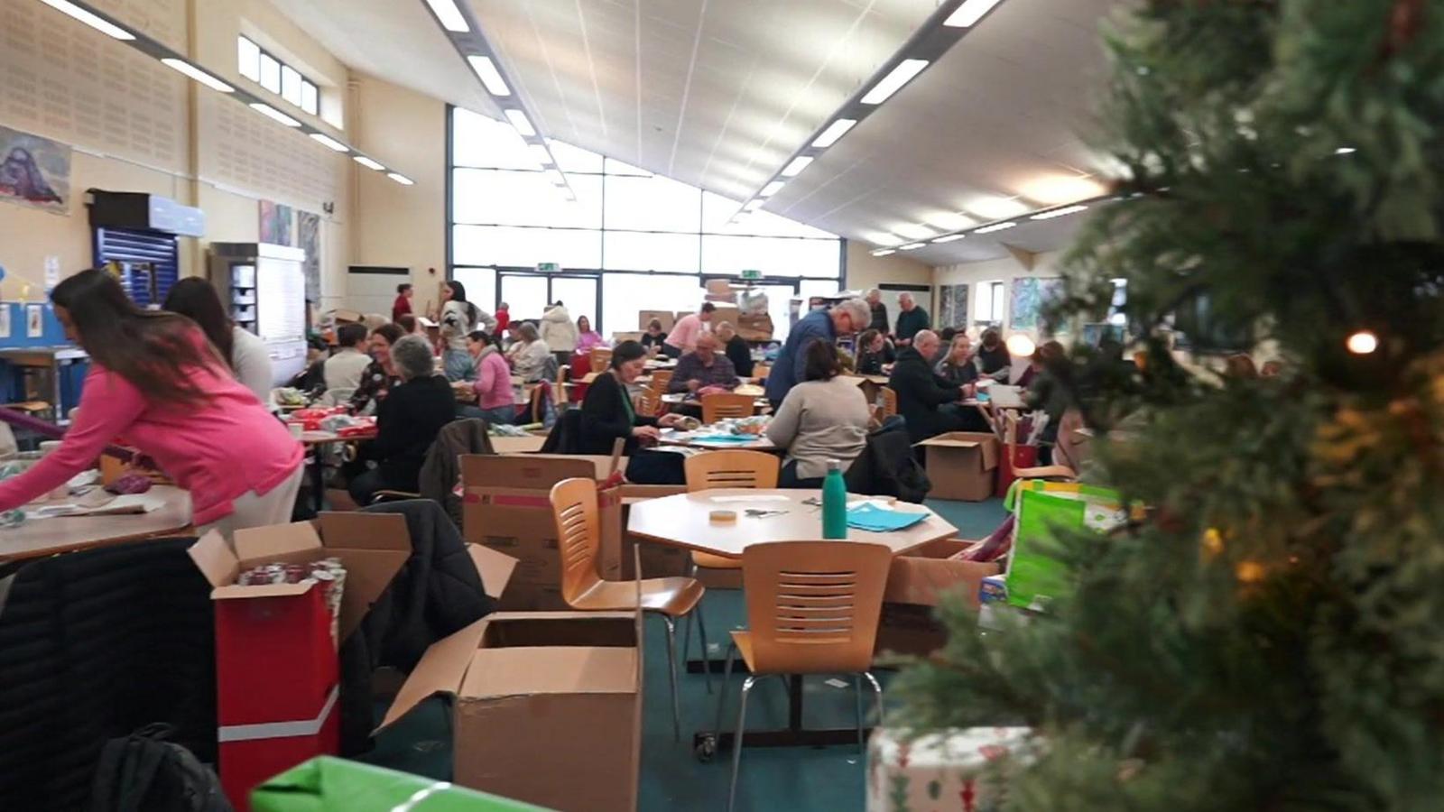 Volunteers at tables wrapping presents