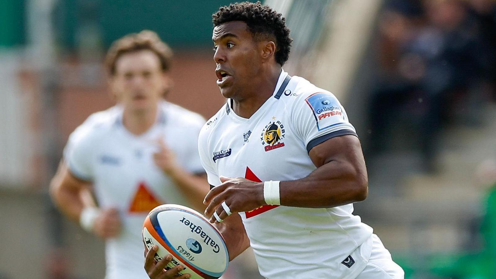 Immanuel Feyi-Waboso wearing a white Exeter shirt with logos on the front in action for the club.