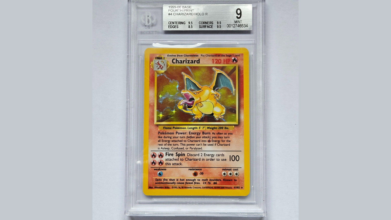 The image shows Mr Free's rare Charizard Pokémon card which is inside a protective, clear case with a sticker detailing the BGA grade of 'mint'. The Pokémon can be seen on the card with information about the creature and its skills from the show.