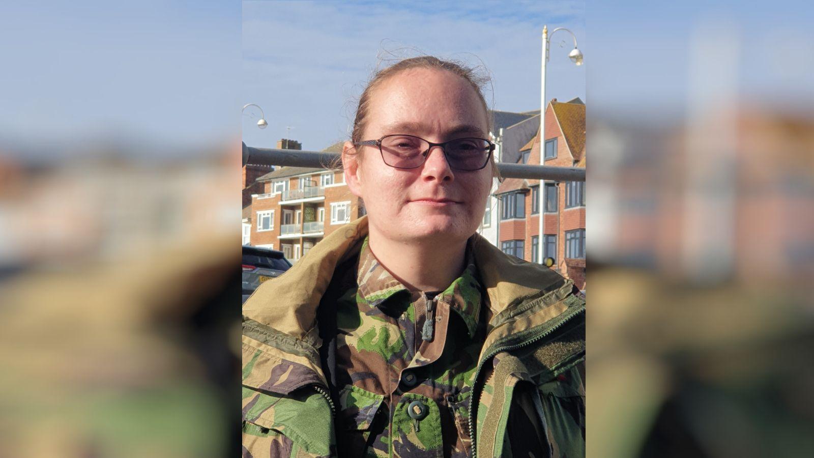 A woman with glasses and a camo jacket. 