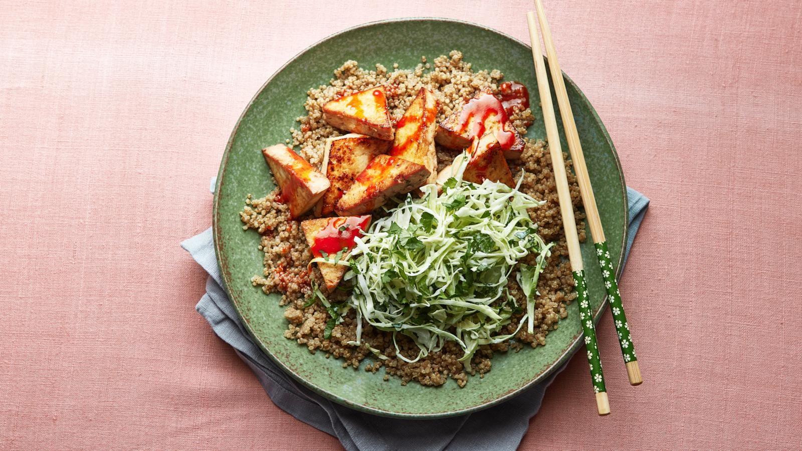 Smoked tofu bowl on a green plate with a blush pink background