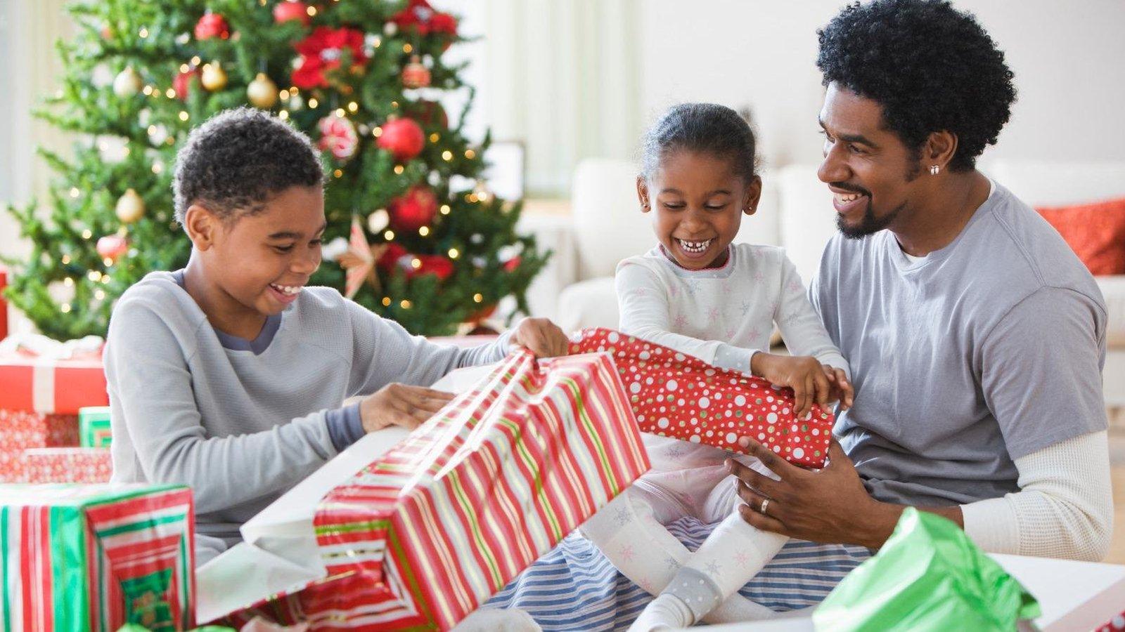 Happy family exchanging Christmas gifts by the tree