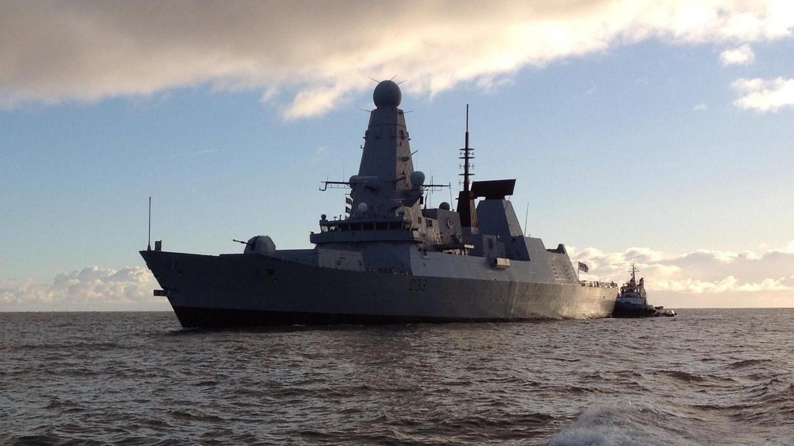 A Type 45 destroyer ship at sea with blue sky behind it.