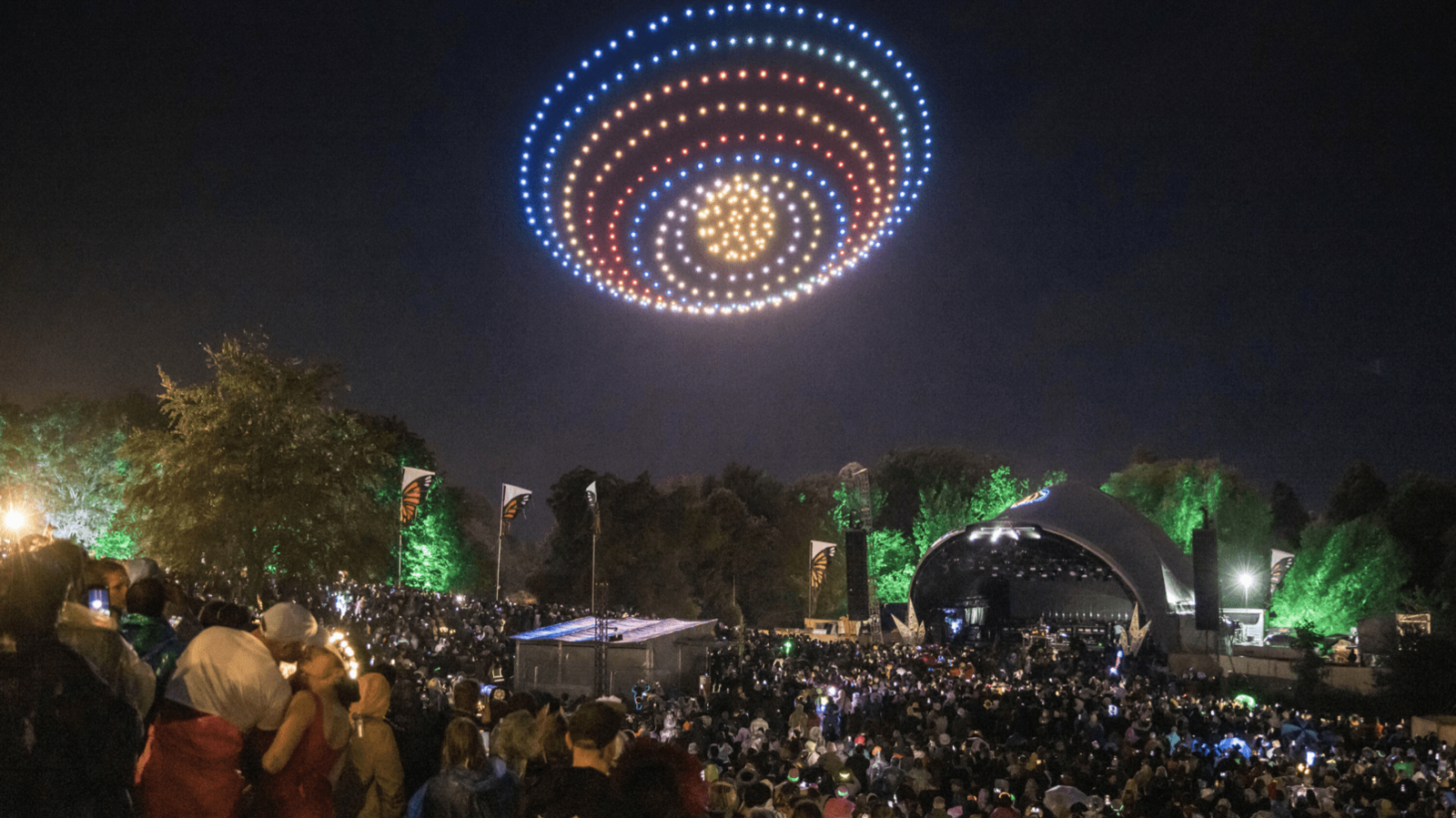 drone fly in a coloured sphere above a festival stage