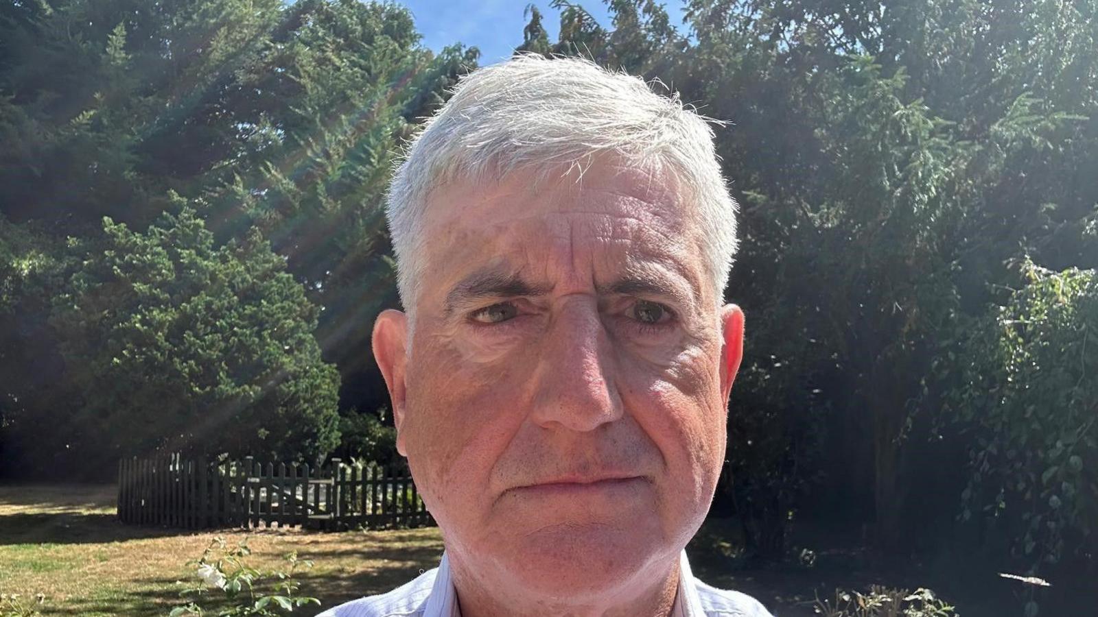 Tony Smith is standing in a park with trees directly behind.