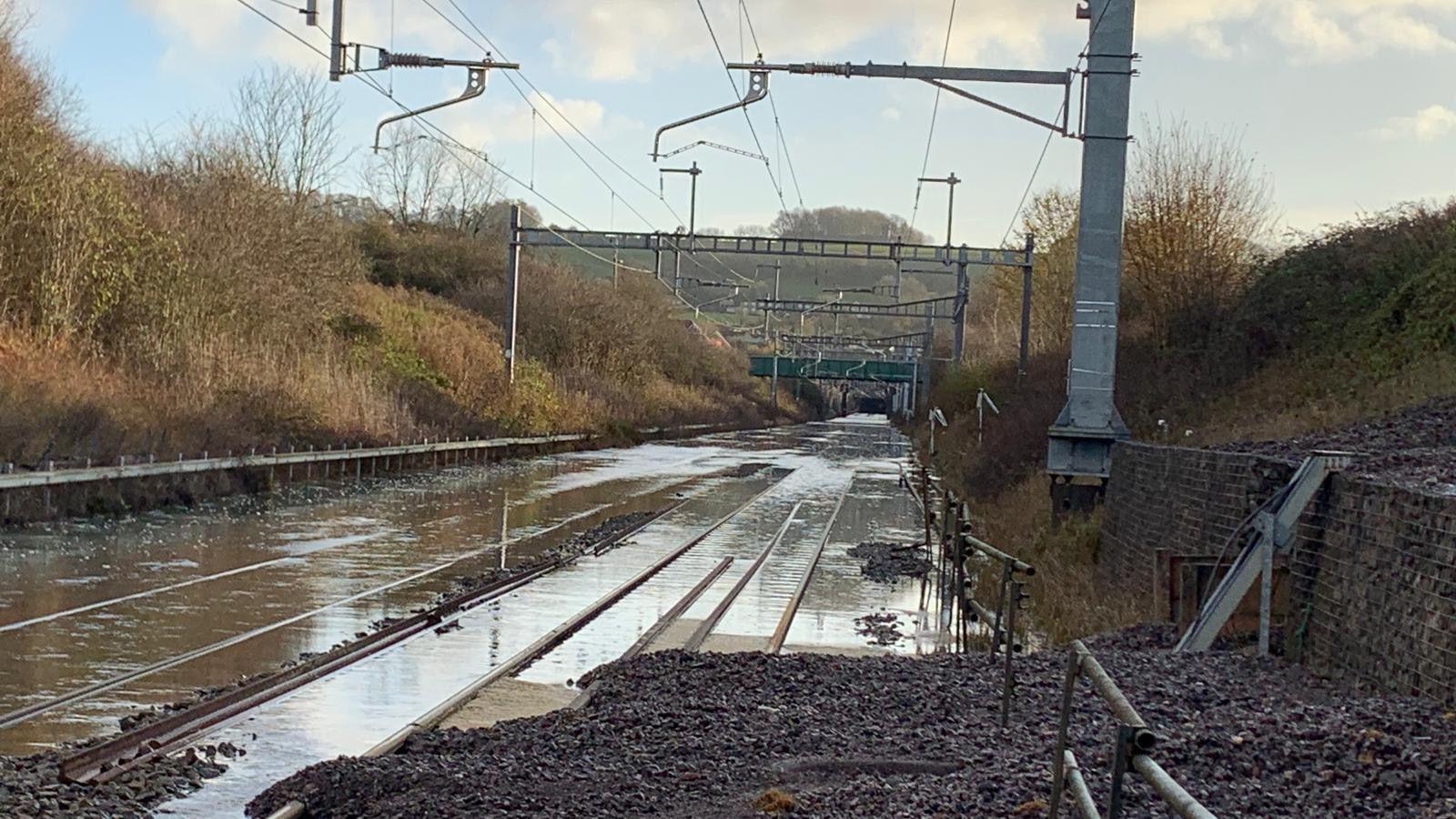 A flooded railway track with trees on either side.