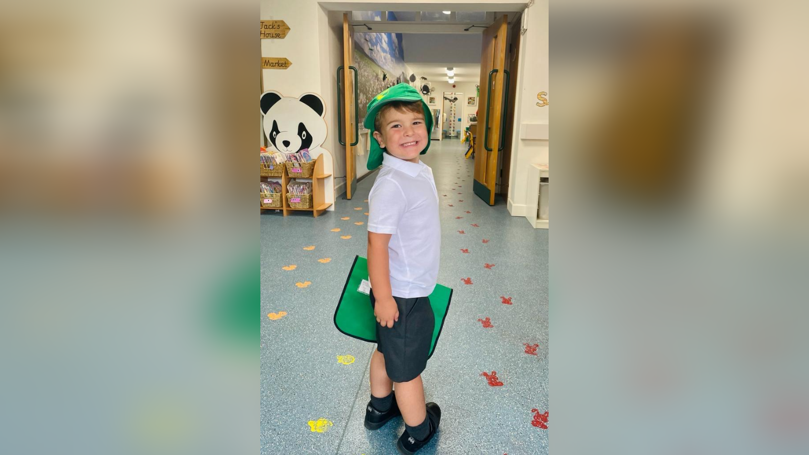 A young boy smiles in a school corridor