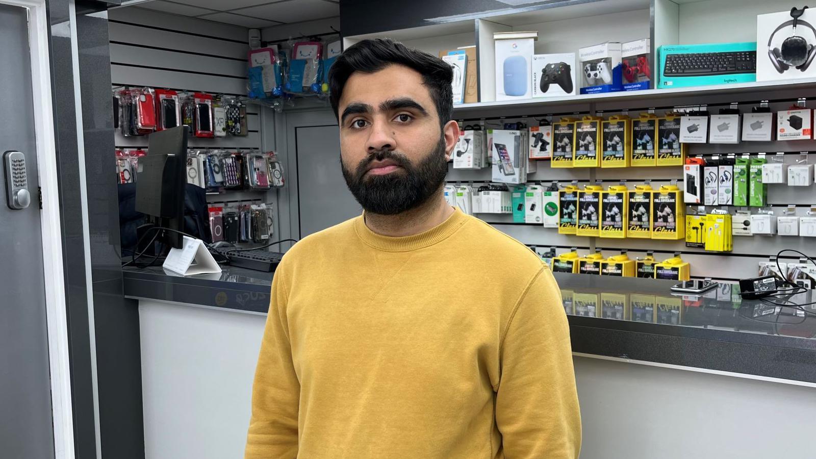 Muhammad Mobeen standing in front of his shop counter