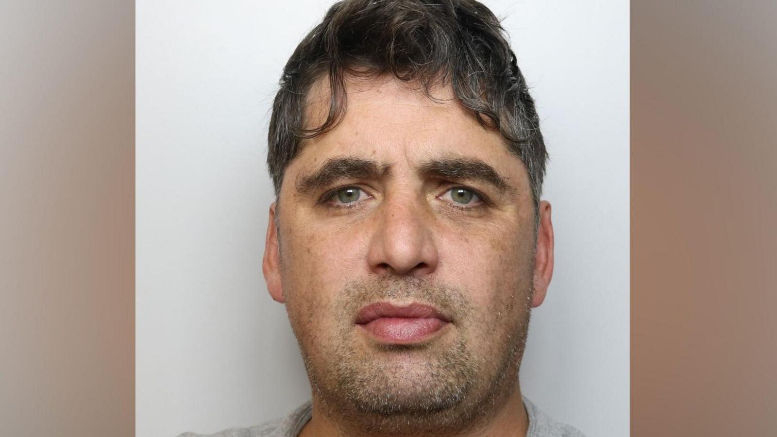 Mugshot of Nathan Cooper, who has wavy dark hair and is wearing a grey top.
