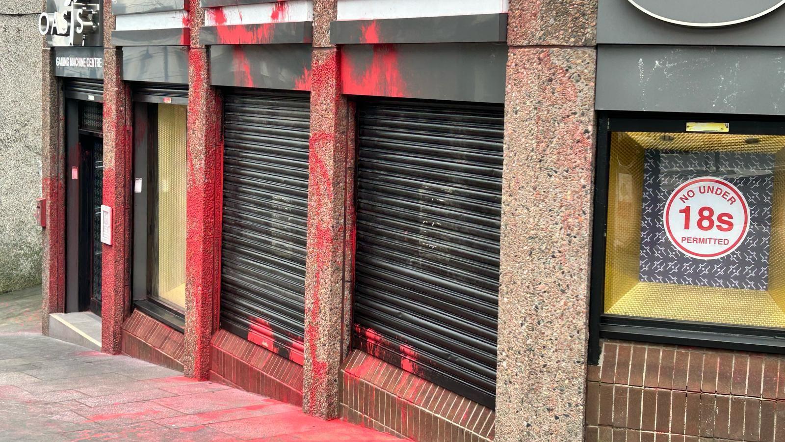 Red paint seen on shopfront with some on the pavement outside