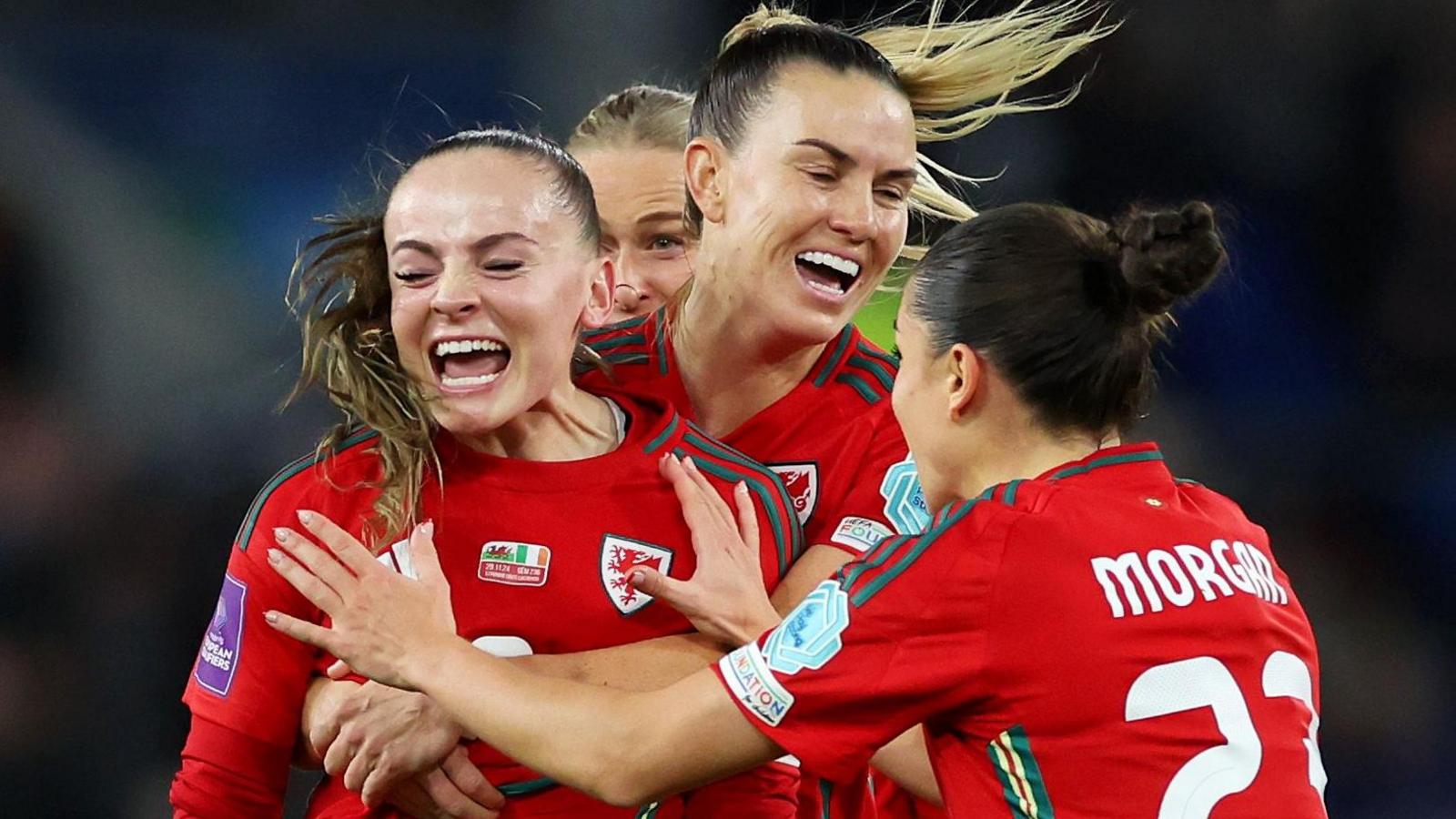 Lily Woodham is mobbed by team-mates after giving Wales the lead