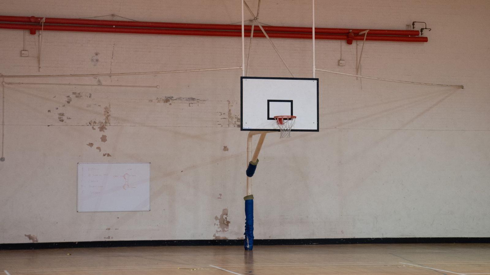 A basketball court at MDP Wethersfield with a tatty wall and a whiteboard.