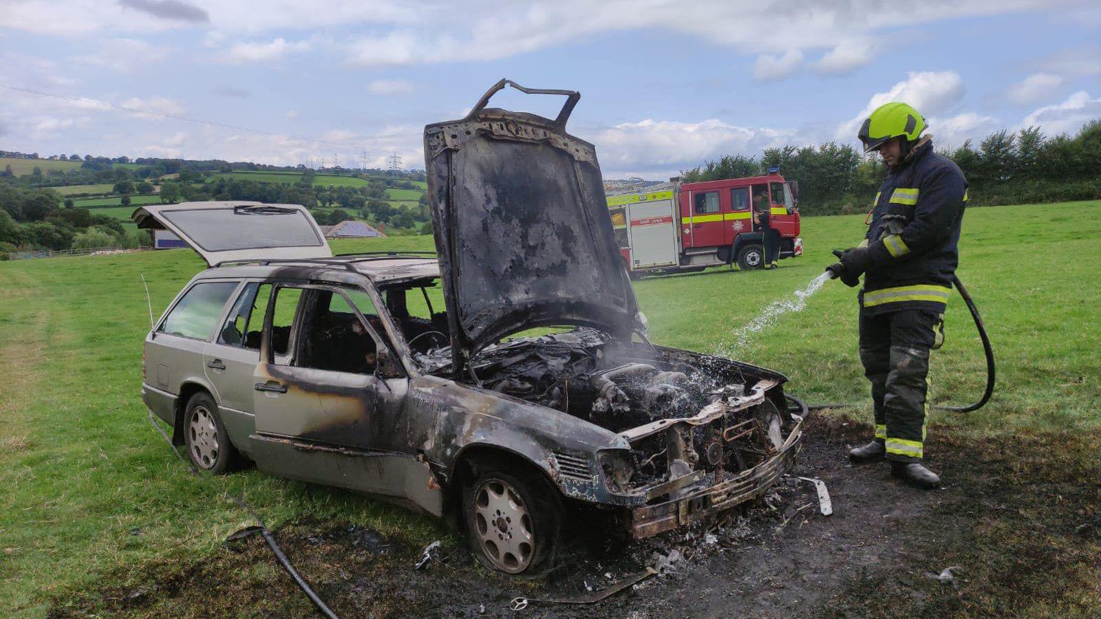 Burnt out car in a field in Dalwood, Devon