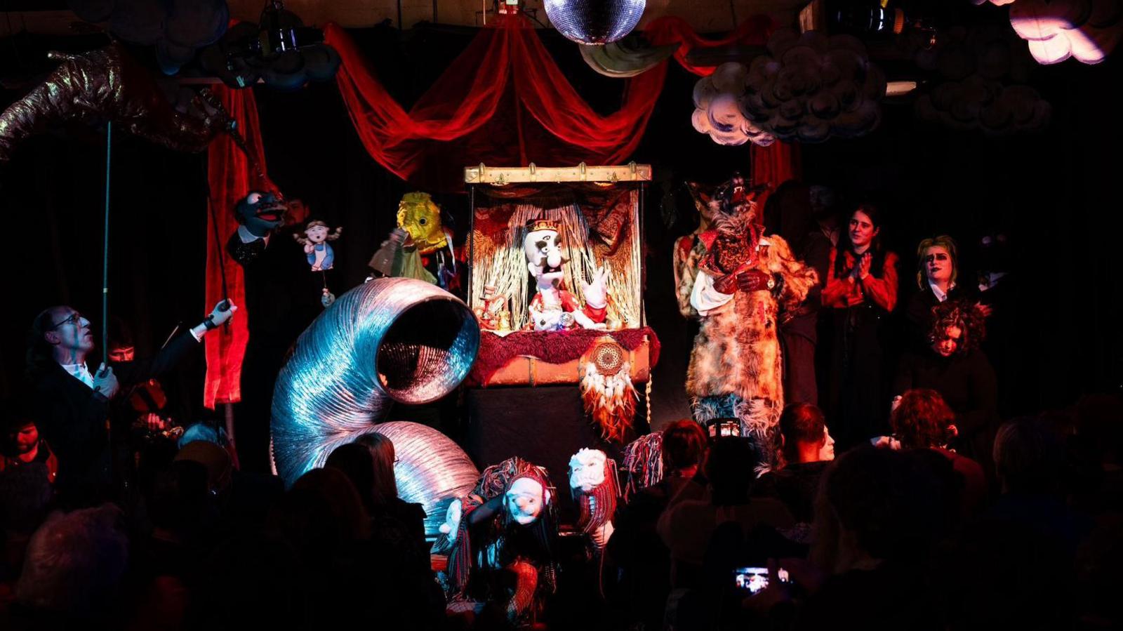 A performance scene at Puppet Place with Kieran's puppet in the centre on stage amongst other performers and their puppets.