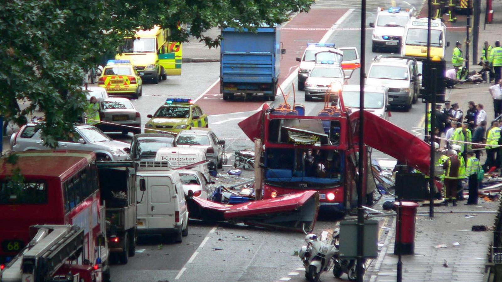 The exploded bus surrounded by debris and first responders.