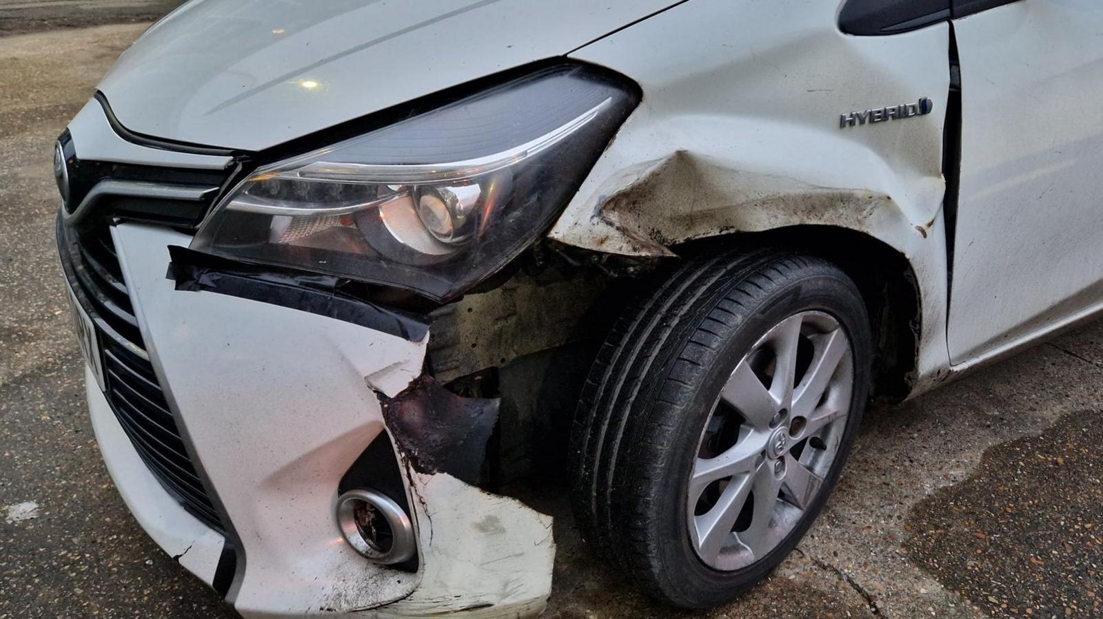 A white car that has damage at the front of it