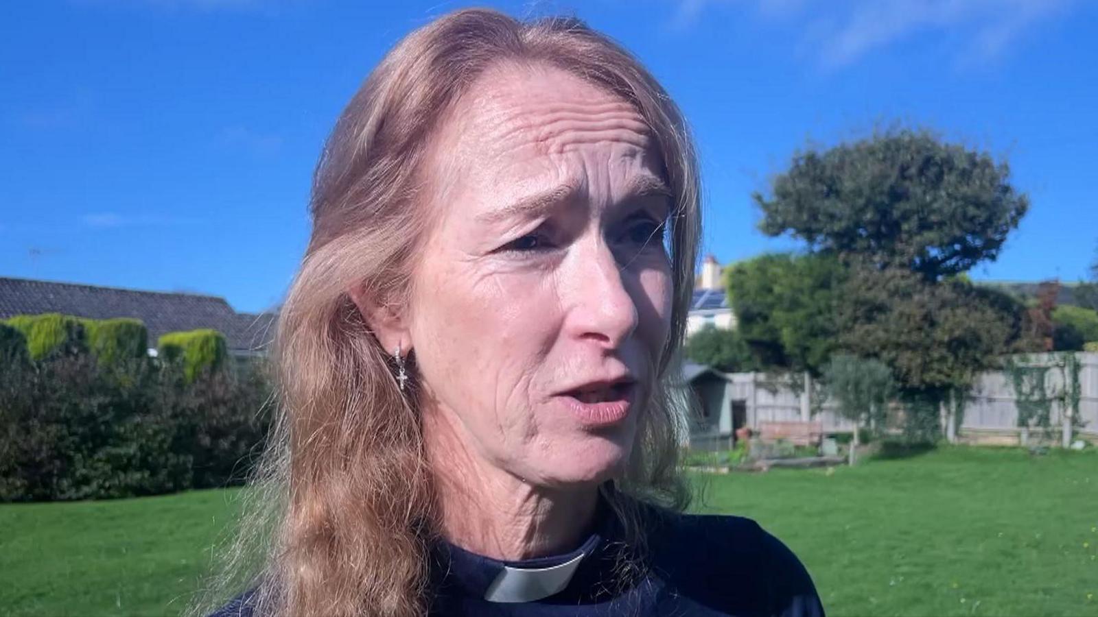 Reverend Jo Levasier talking to the camera in the garden on the church