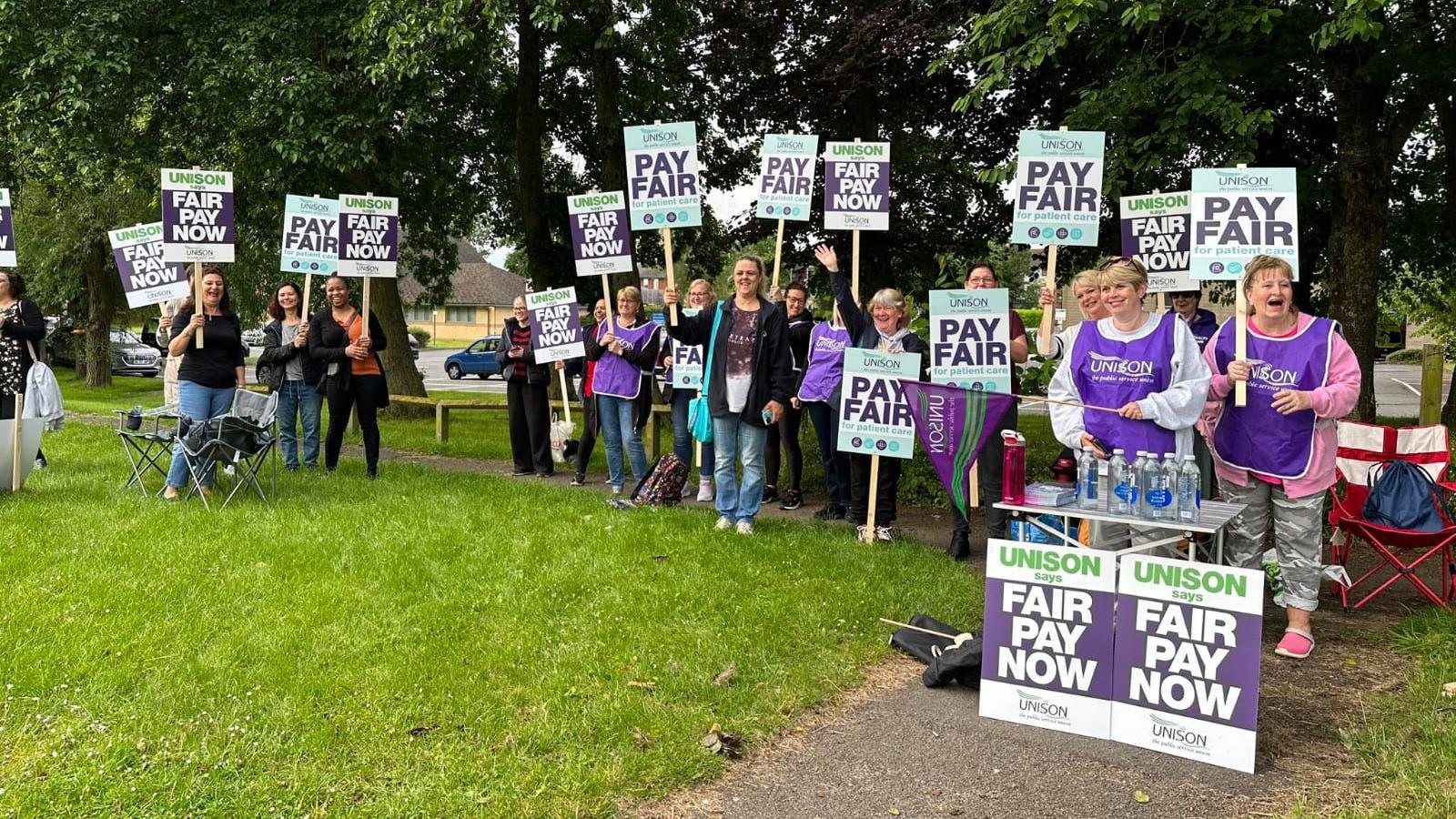 NHS staff protesting outside the hospital with boards and signs 