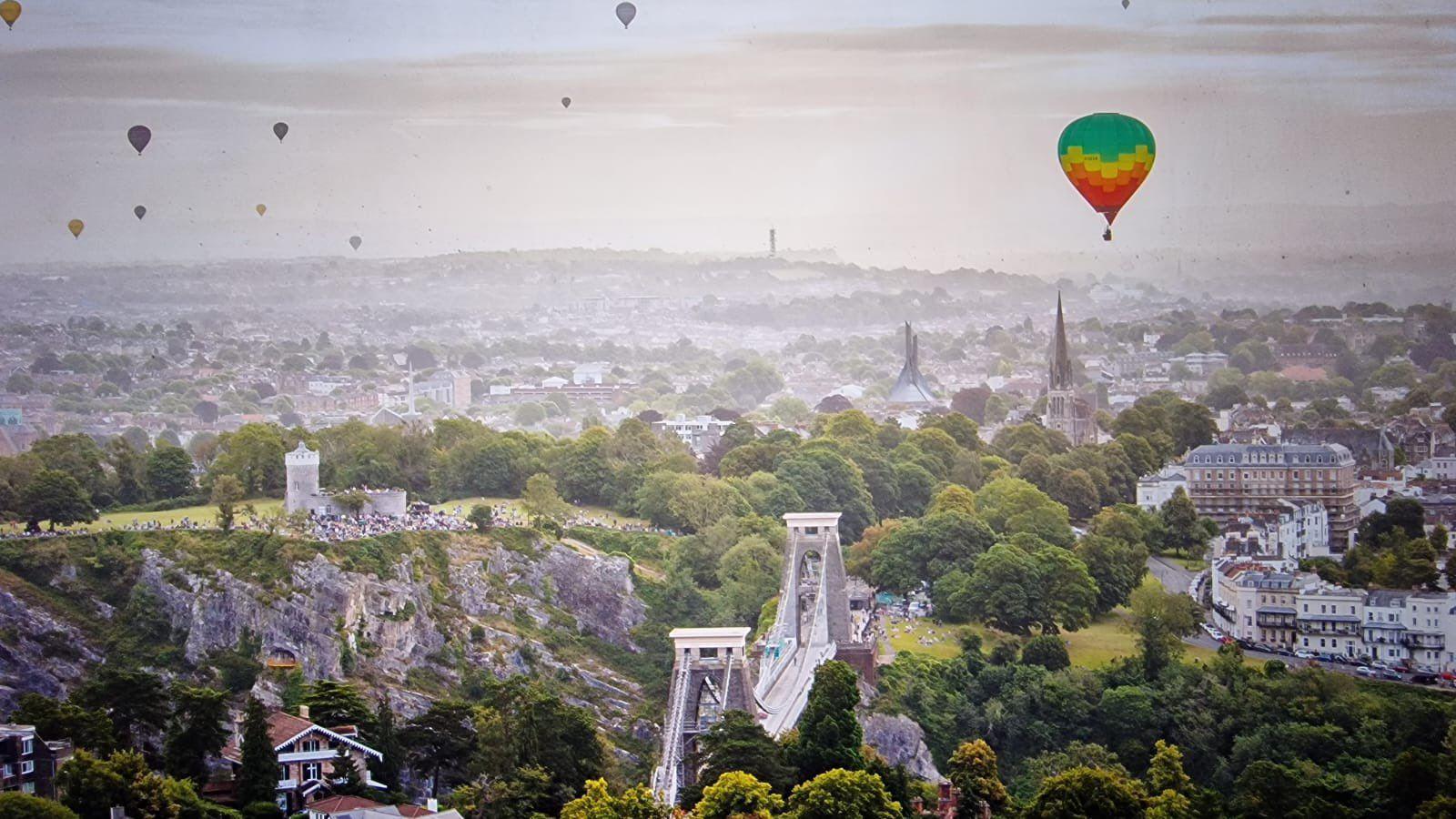 A series of balloons in the sky over Bristol with the Clifton Suspension Bridge in the foreground