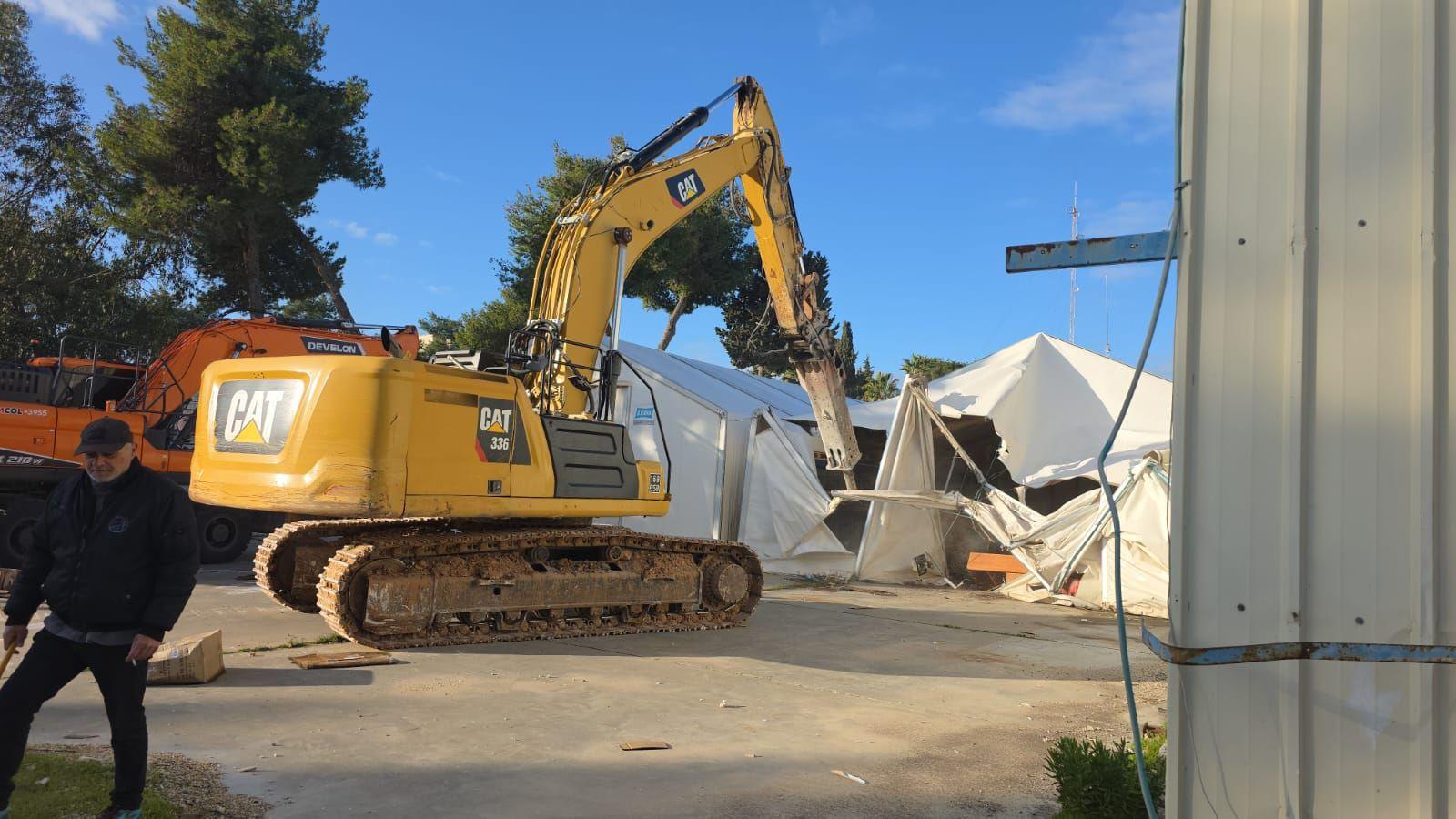 A yellow excavator tears down a white tented structure at the Unrwa compound in East Jerusalem (20/01/26)