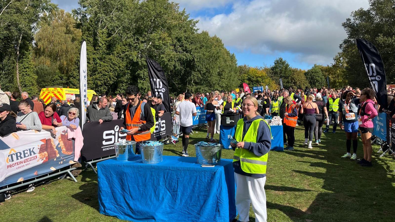 Groups gathering after the half marathon in Swindon. A person is stood at a table handing out medals.