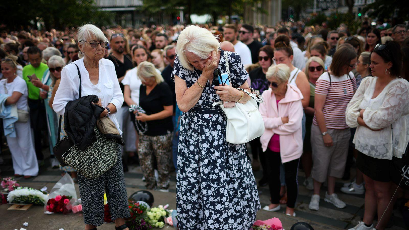 A woman wipes tears from her eyes as she looks at flowers that have been left for the victims of the Southport stabbing