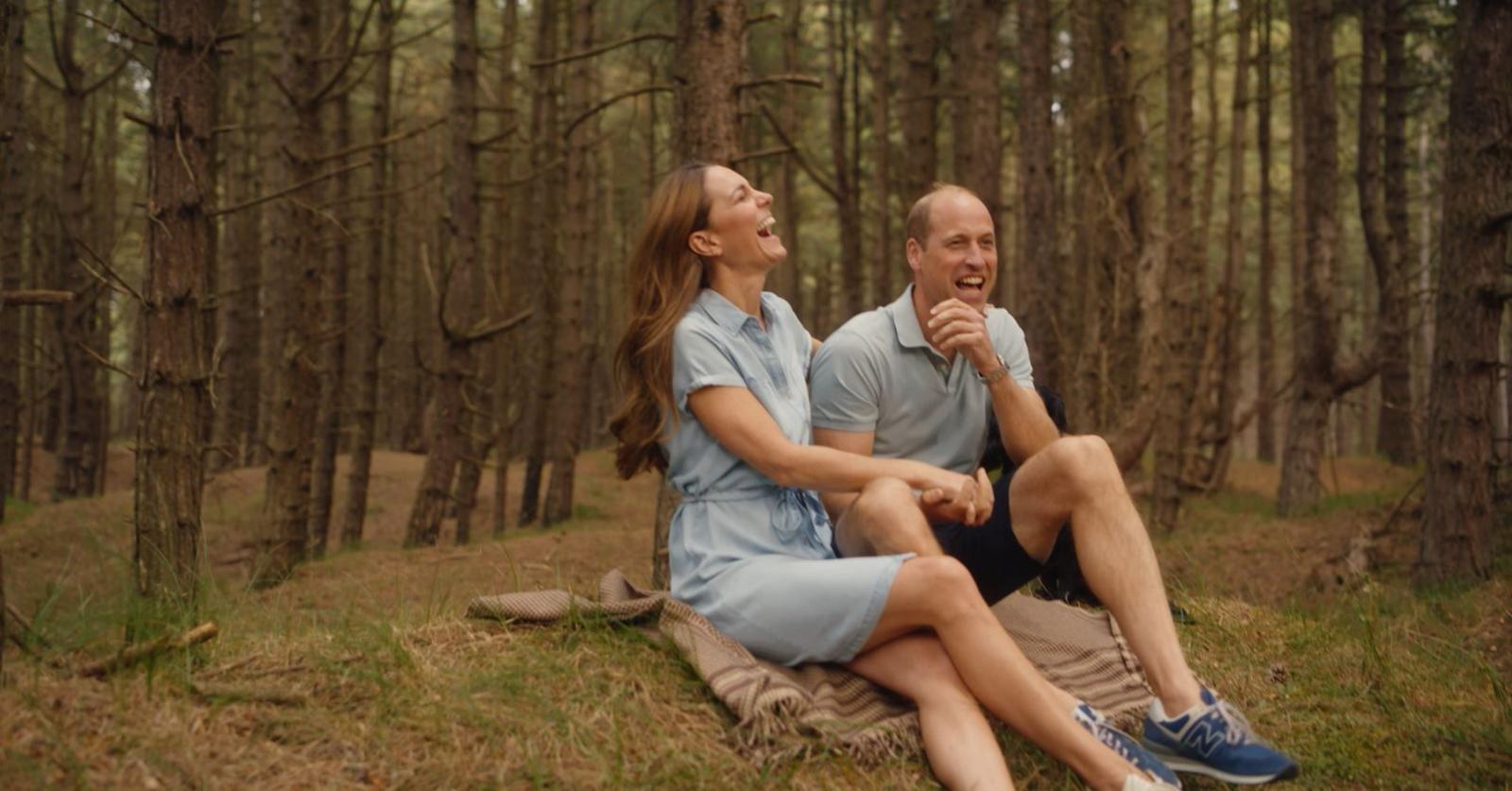 The Prince and Princess of Wales laugh while in a forest scene sitting on a blanket 