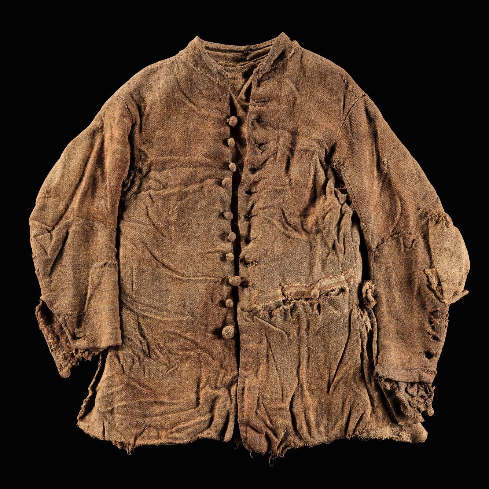 The entire jacket is shown against a black background. It is brown and the fabric is crumpled. There are buttons on the jacket.