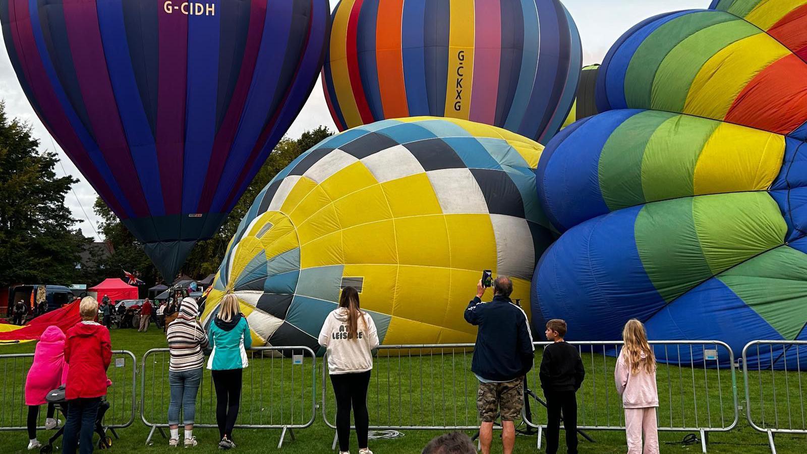 People standing around hot air balloons on the ground