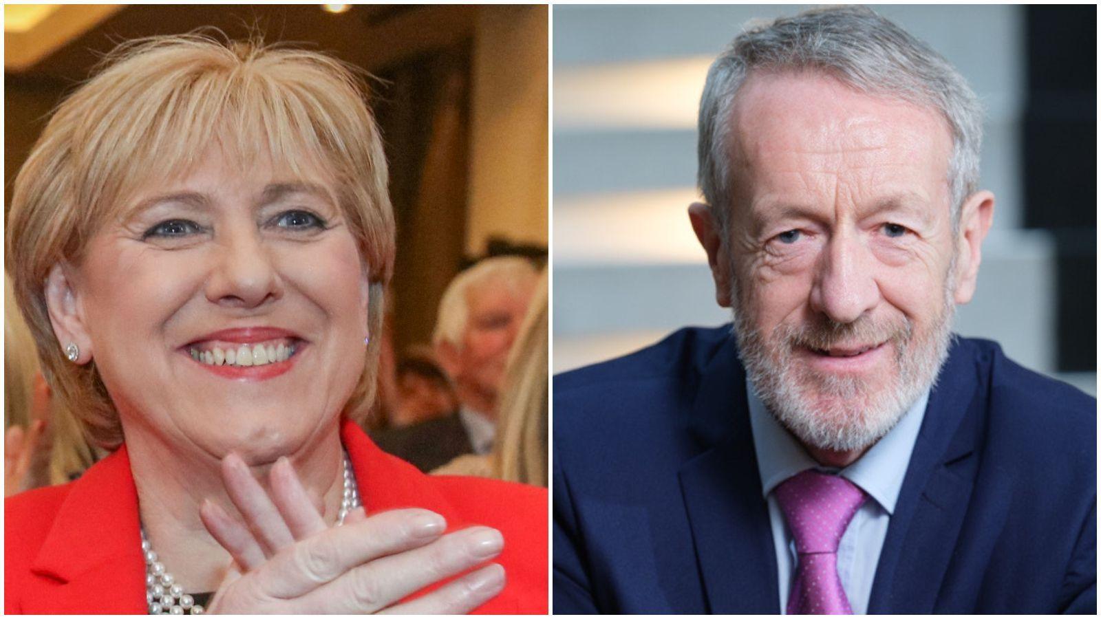 A blonde haired woman in red claps her hands, while a grey haired man is on the right and wears a purple tie.
