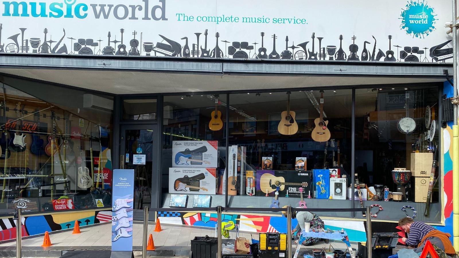 A photo showing the exterior of the Music World shop which is being painted by an artist as part of the festival