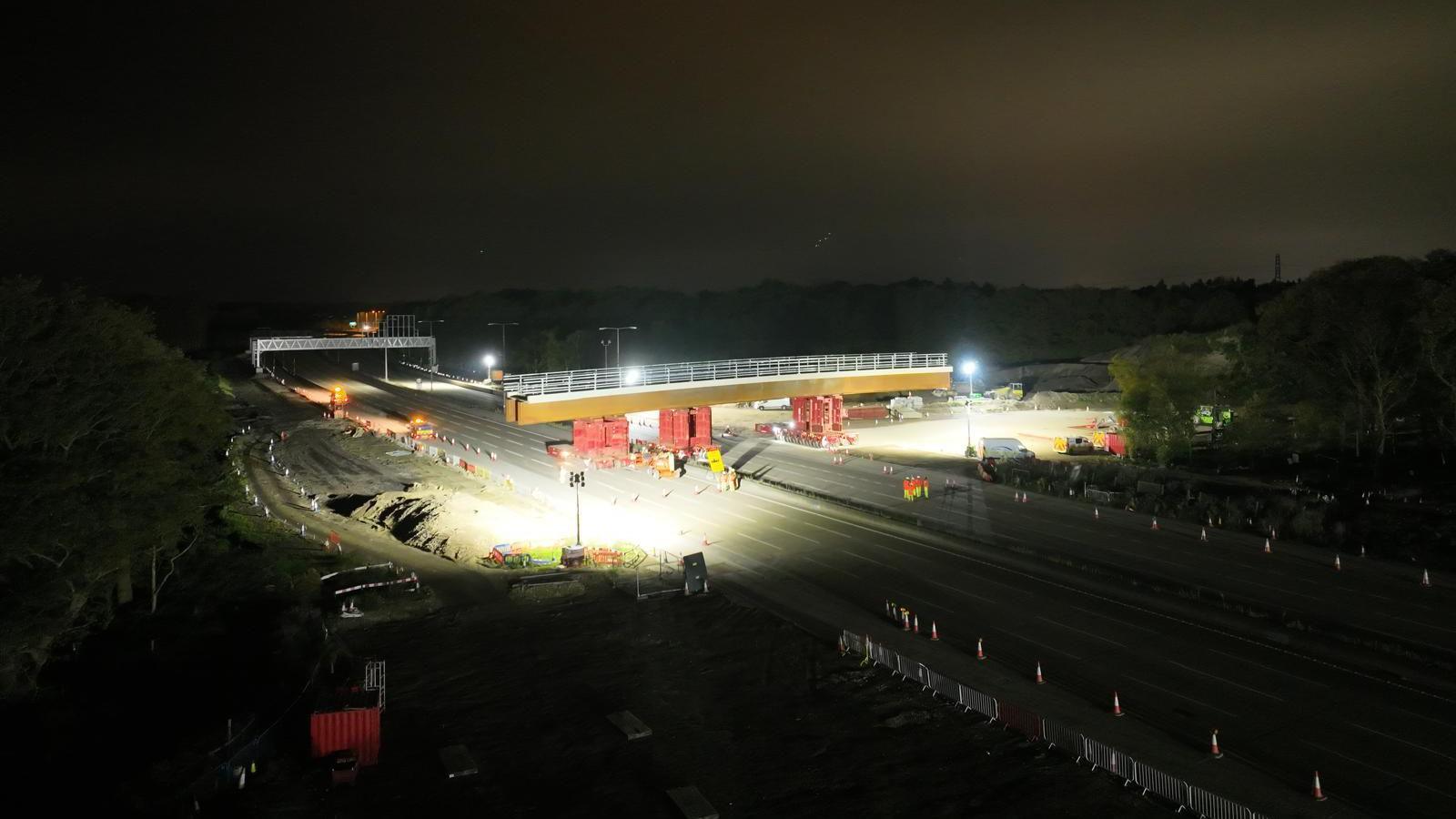 Workers install the new Clearmount bridge across the road at night