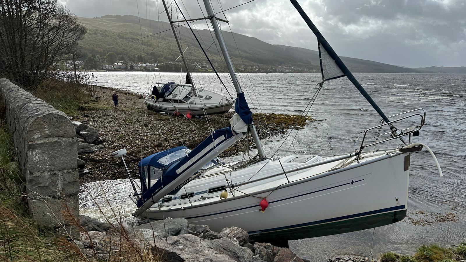 Two yachts by a shoreline with stormy grey skies in the background