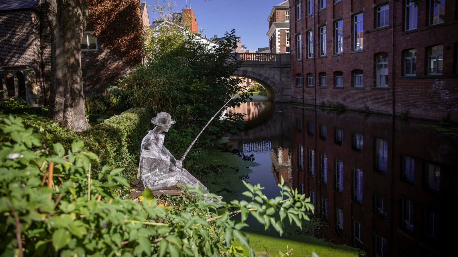 A ghost sculpture of a man fishing sits by the river in York.