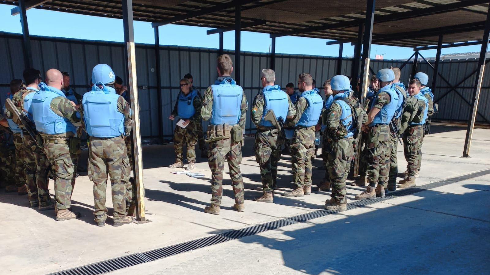 A number of Irish peacekeepers being briefed during a recent clearance operation in Lebanon.   A group of soldiers wearing camouflage uniforms with light blue UN helmets and flak jackets are standing in a circle listening to instructions. 