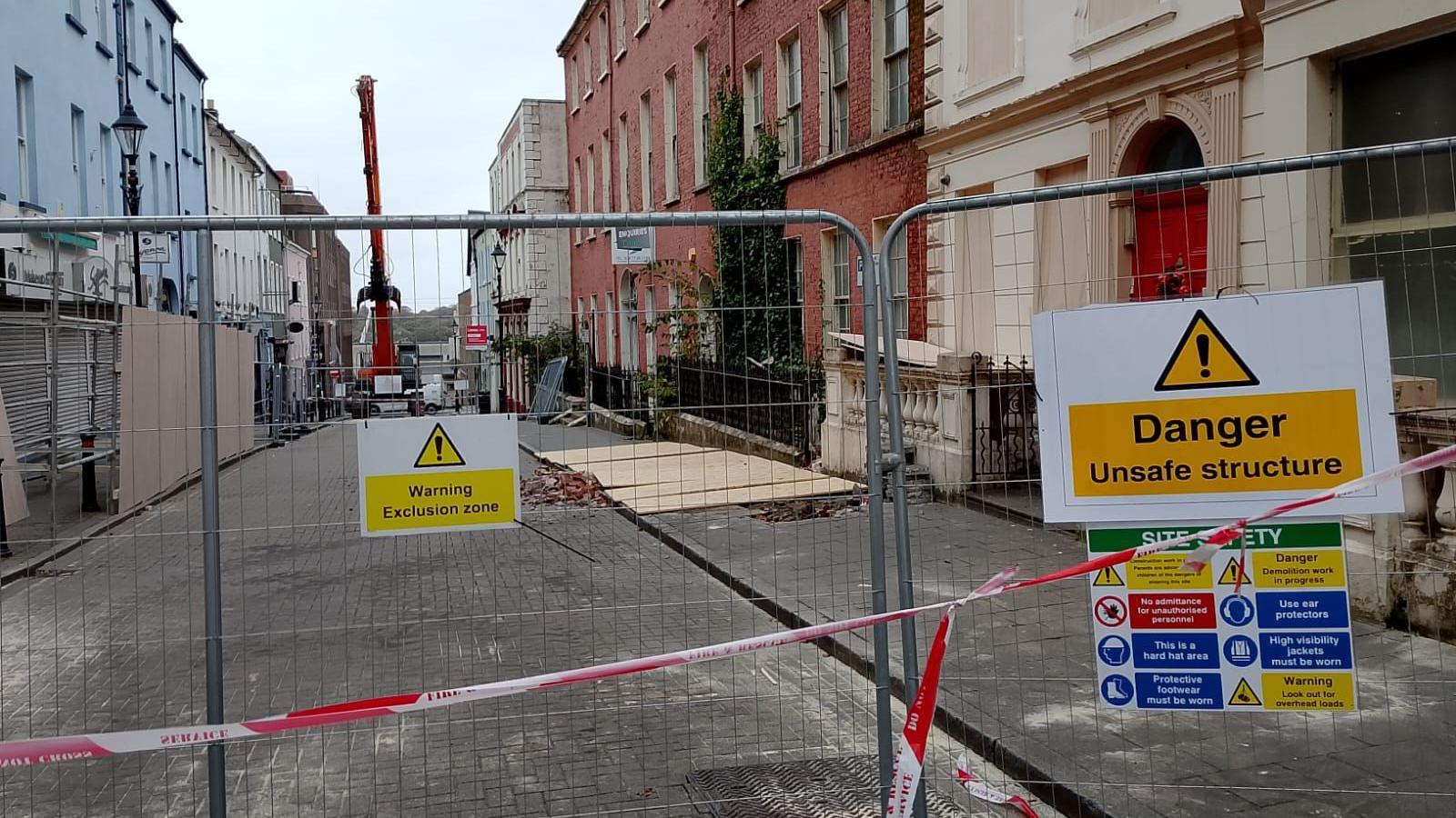 A large cordon is in the middle of a street with a crane visible in the background. 